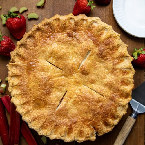 Whole Strawberry Rhubarb Pie on a wooden table from overhead.