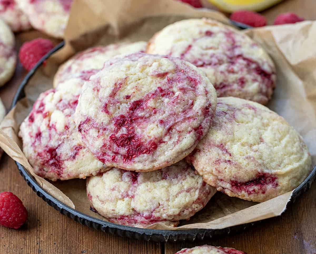 Plate of Lemon Raspberry Cookies with fresh raspberry and lemon slices on a wooden table.