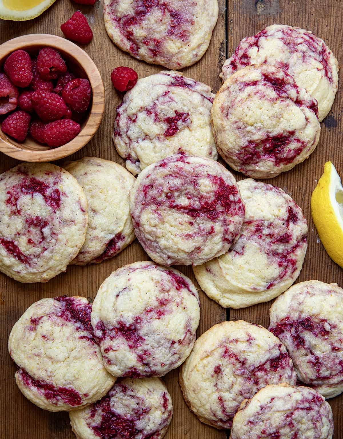 Lemon Raspberry Cookies with fresh raspberry and lemon wedges on a wooden table from overhead.