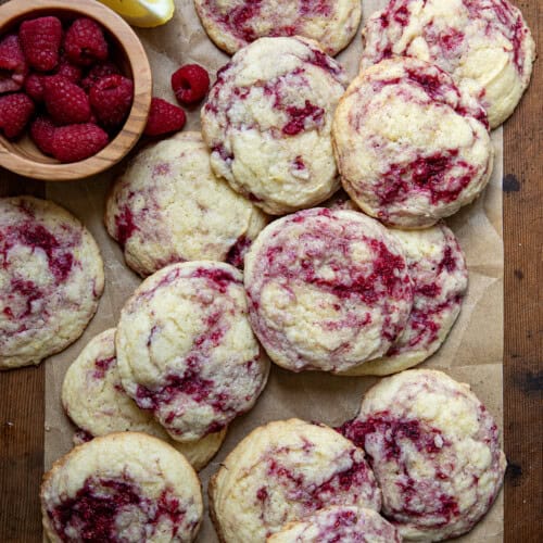 Lemon Raspberry Cookies with fresh raspberry and lemon wedges on a wooden table from overhead.