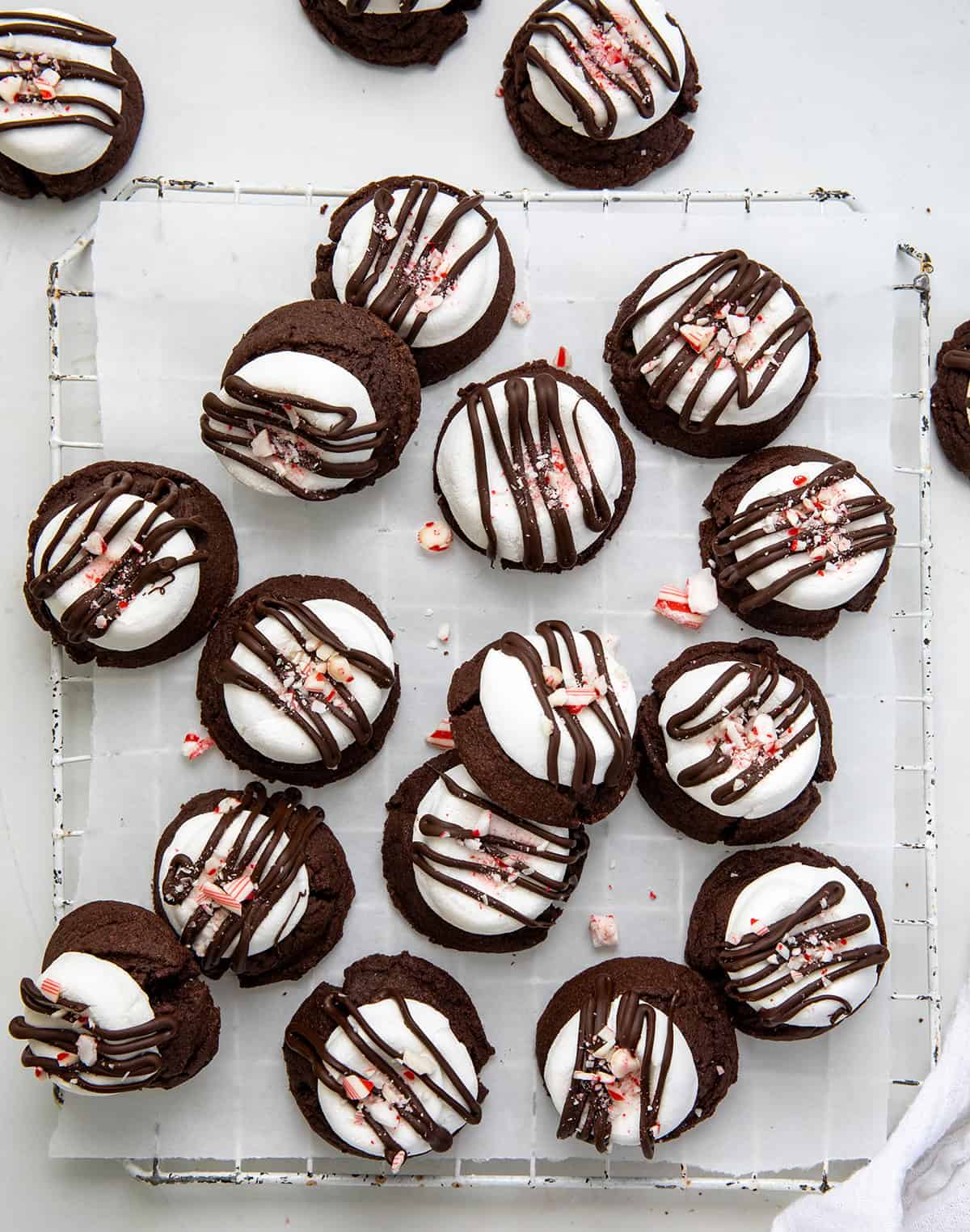 Peppermint Hot Chocolate Cookies on a cooling rack covered in white parchment paper with pieces of candy canes around from overhead.