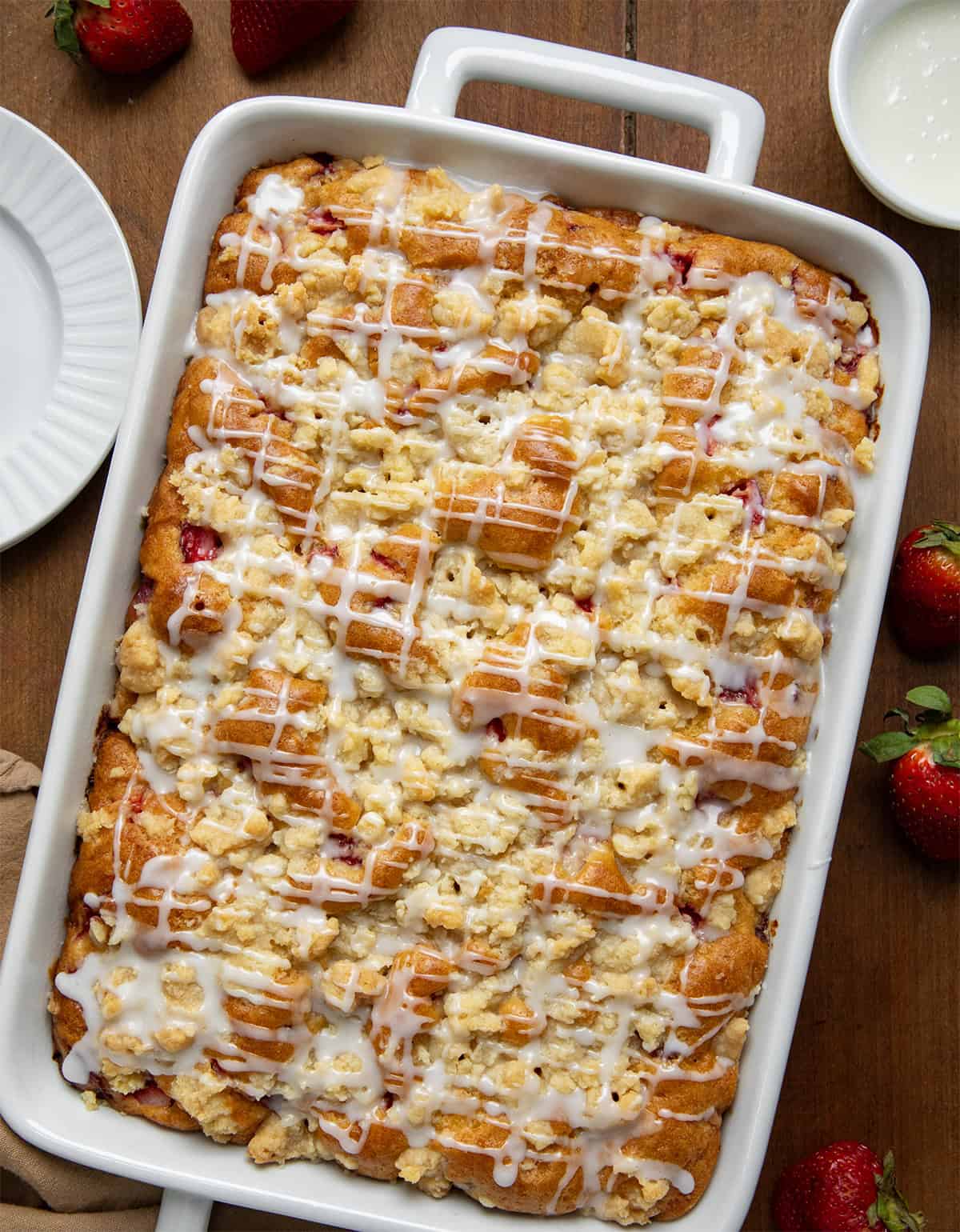 White pan of Strawberry Crumb Cake on a wooden table from overhead.