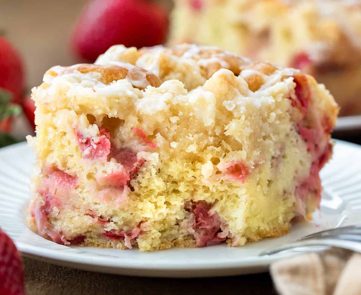 One piece of Strawberry Crumb Cake on a white plate with a bite removed and fork resting on the side of the plate.