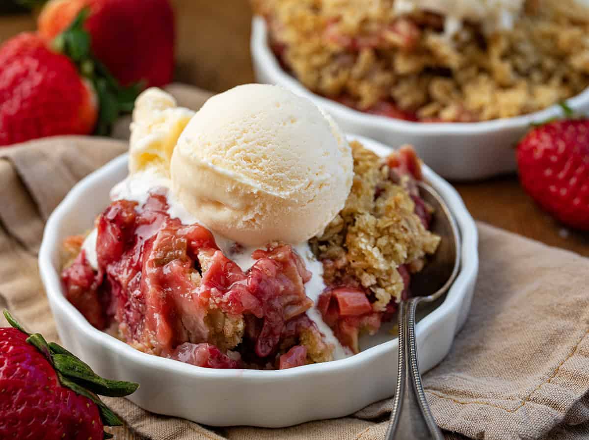 Bowls of Strawberry Rhubarb Crisp with a spoon and ice cream.