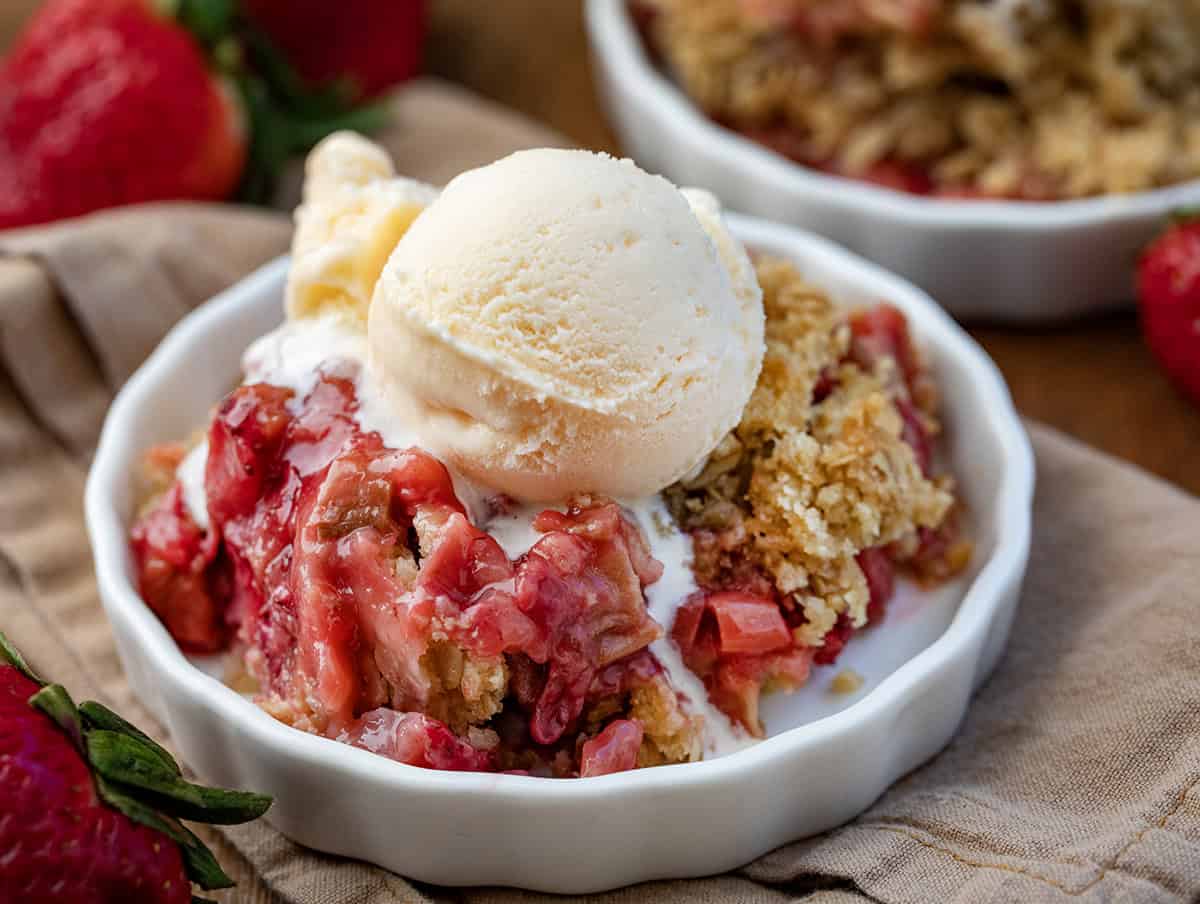 Bowls of Strawberry Rhubarb Crisp with a spoon and ice cream.