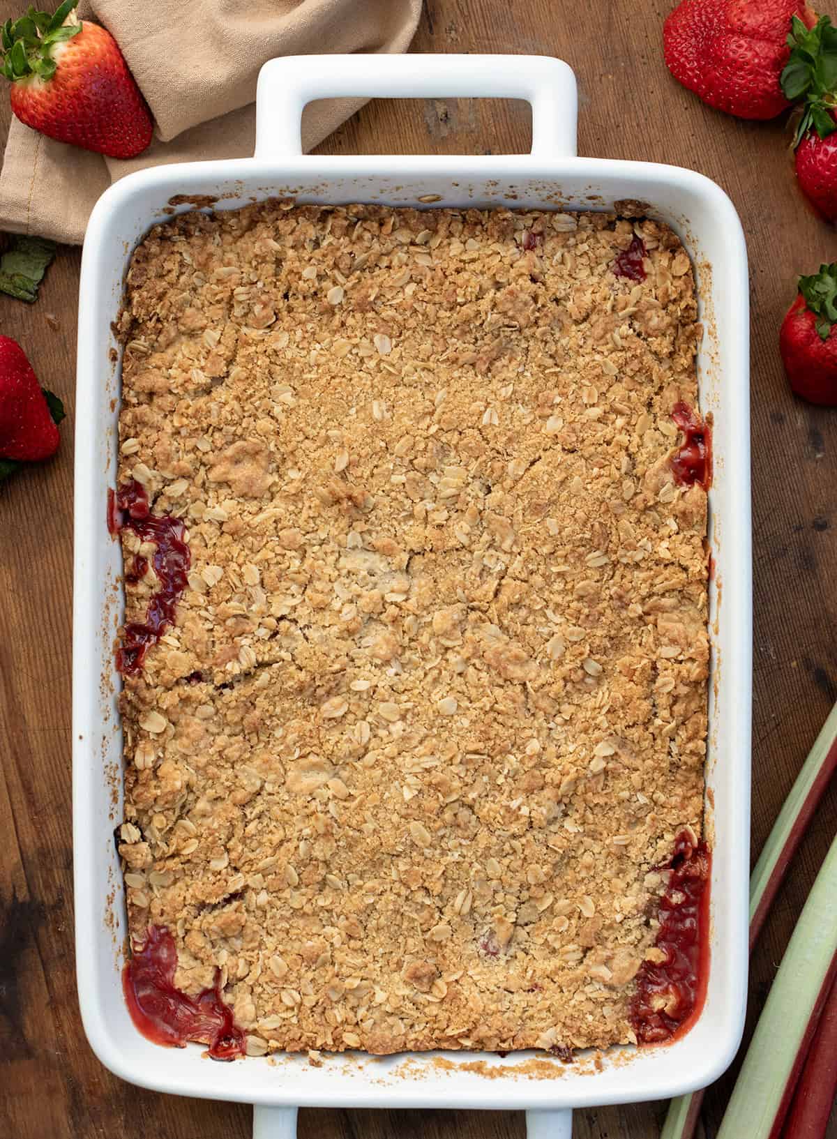 Pan of Strawberry Rhubarb Crisp on a wooden table from overhead.