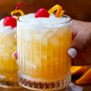 Hand holding a glass filled with the Amaretto Sour drink.