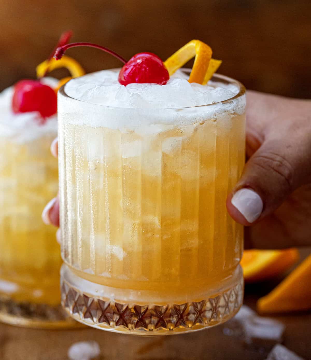 Hand holding a glass filled with the Amaretto Sour drink.