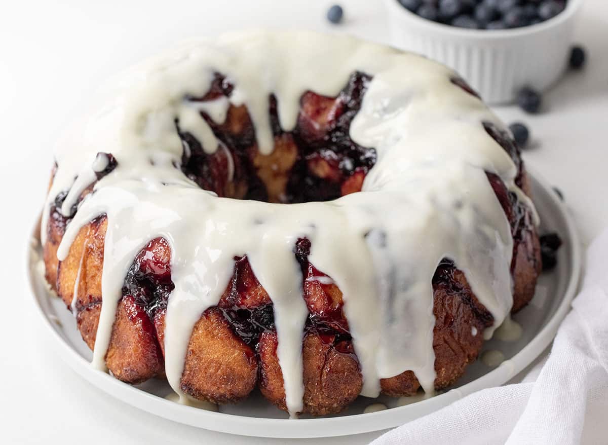 Blueberry Monkey Bread with a Vanilla Glaze on a white plate on a white counter.