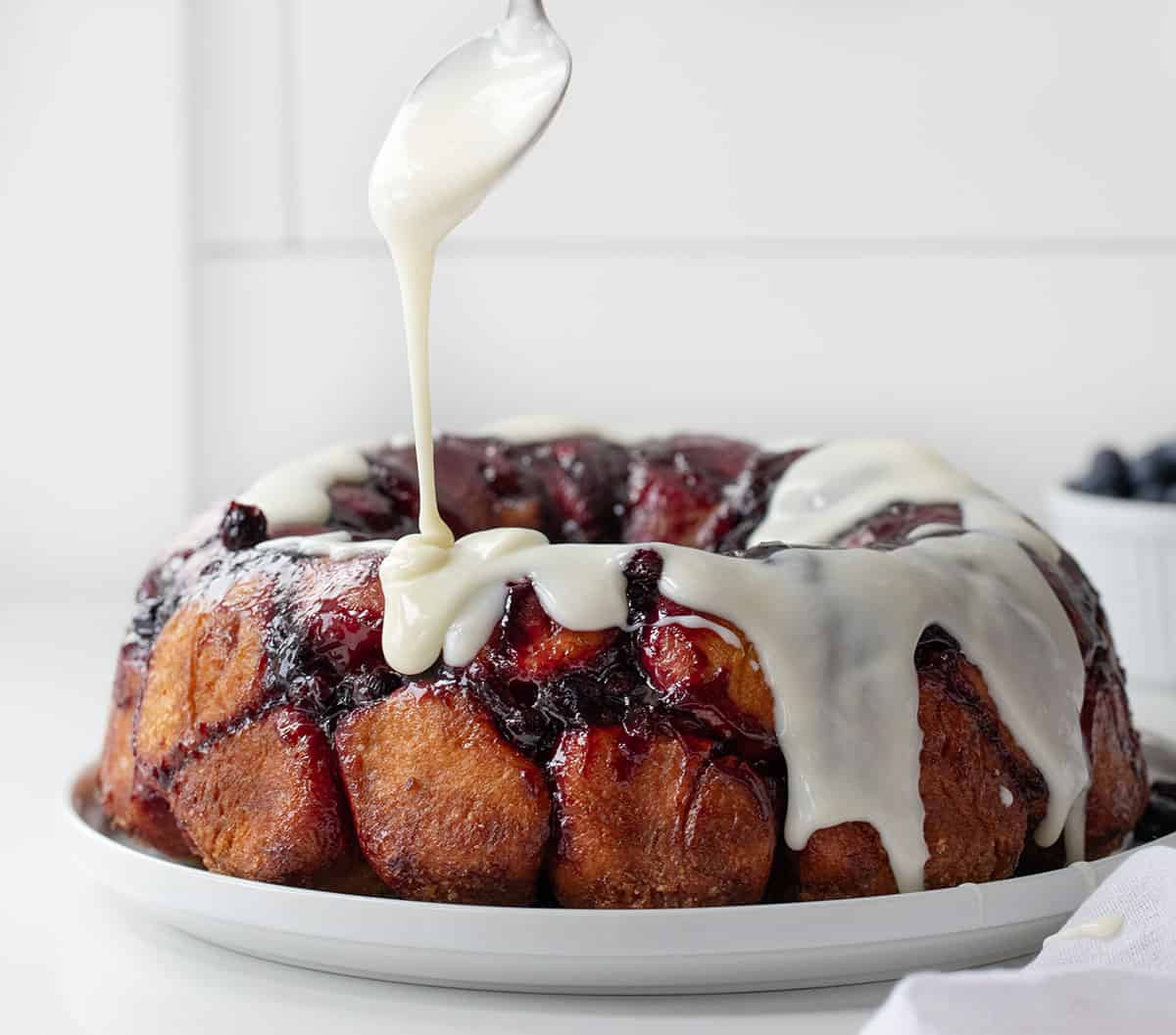 Drizzling glaze over Blueberry Monkey Bread.