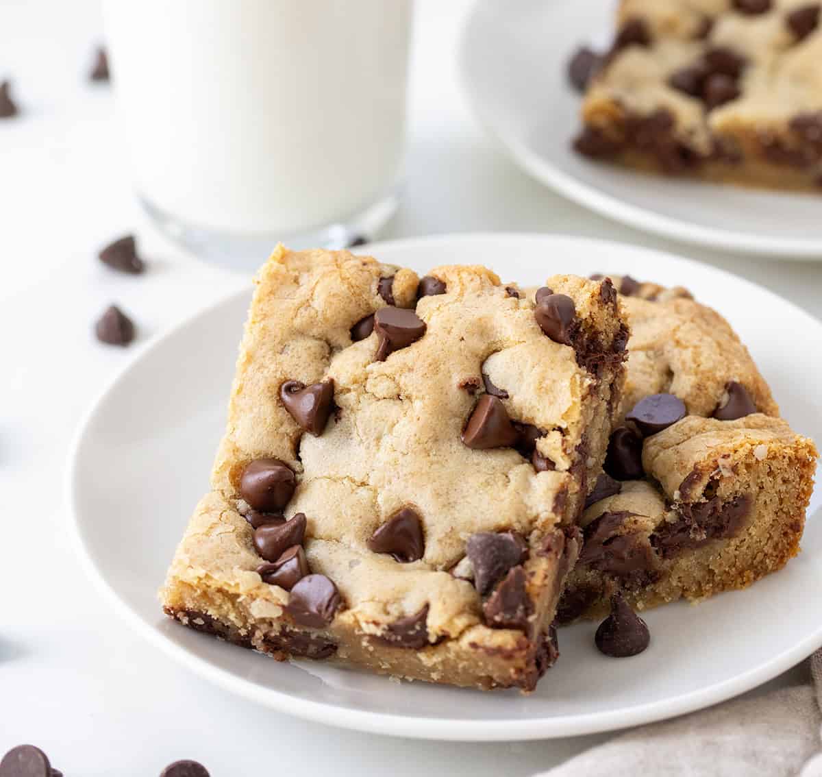 Browned Butter Chocolate Chip Cookie Bars on a white plate with a glass of milk.