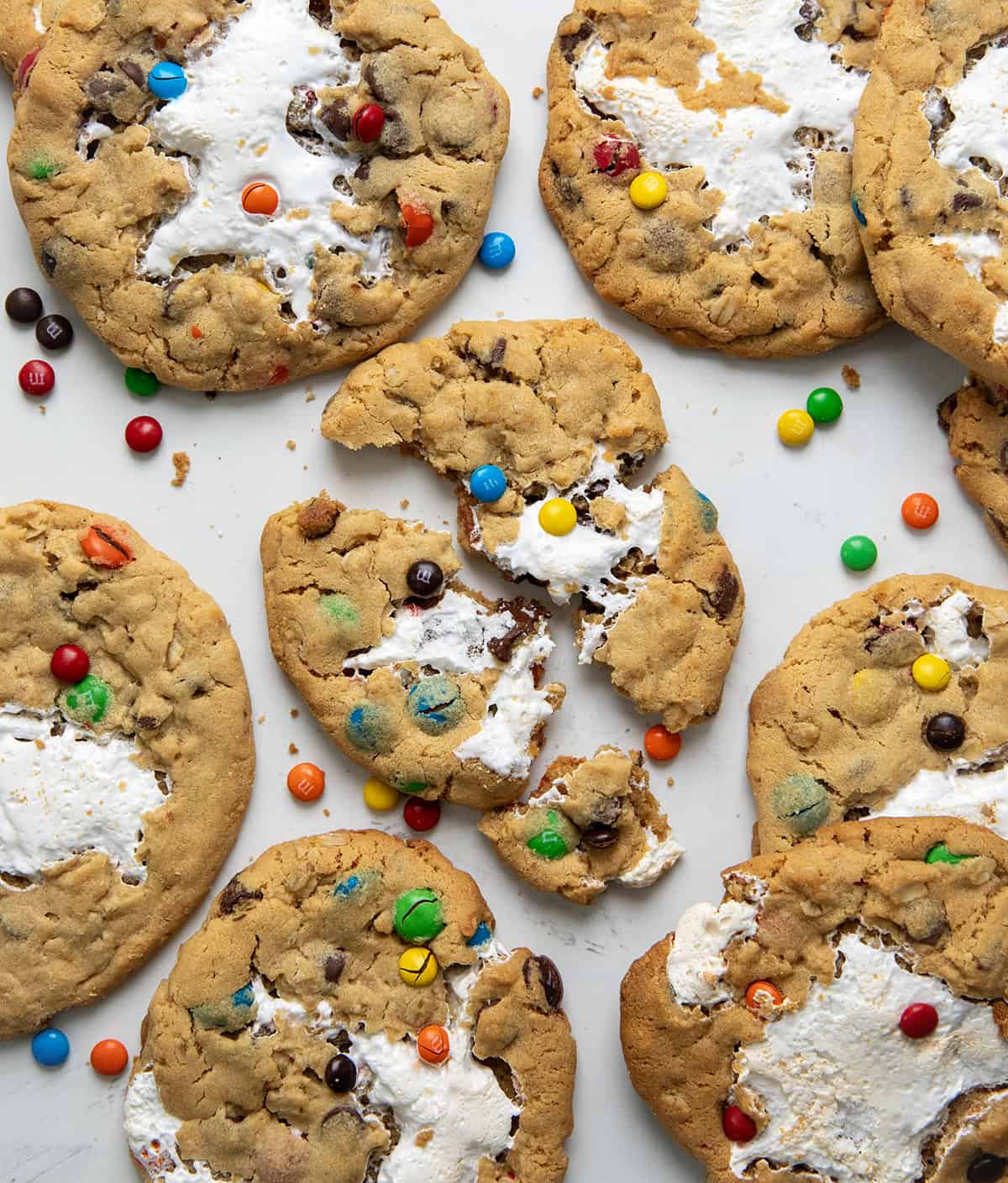 Marshmallow Monster Cookies on a white table with center cookie broken in half showing gooey marshmallow.