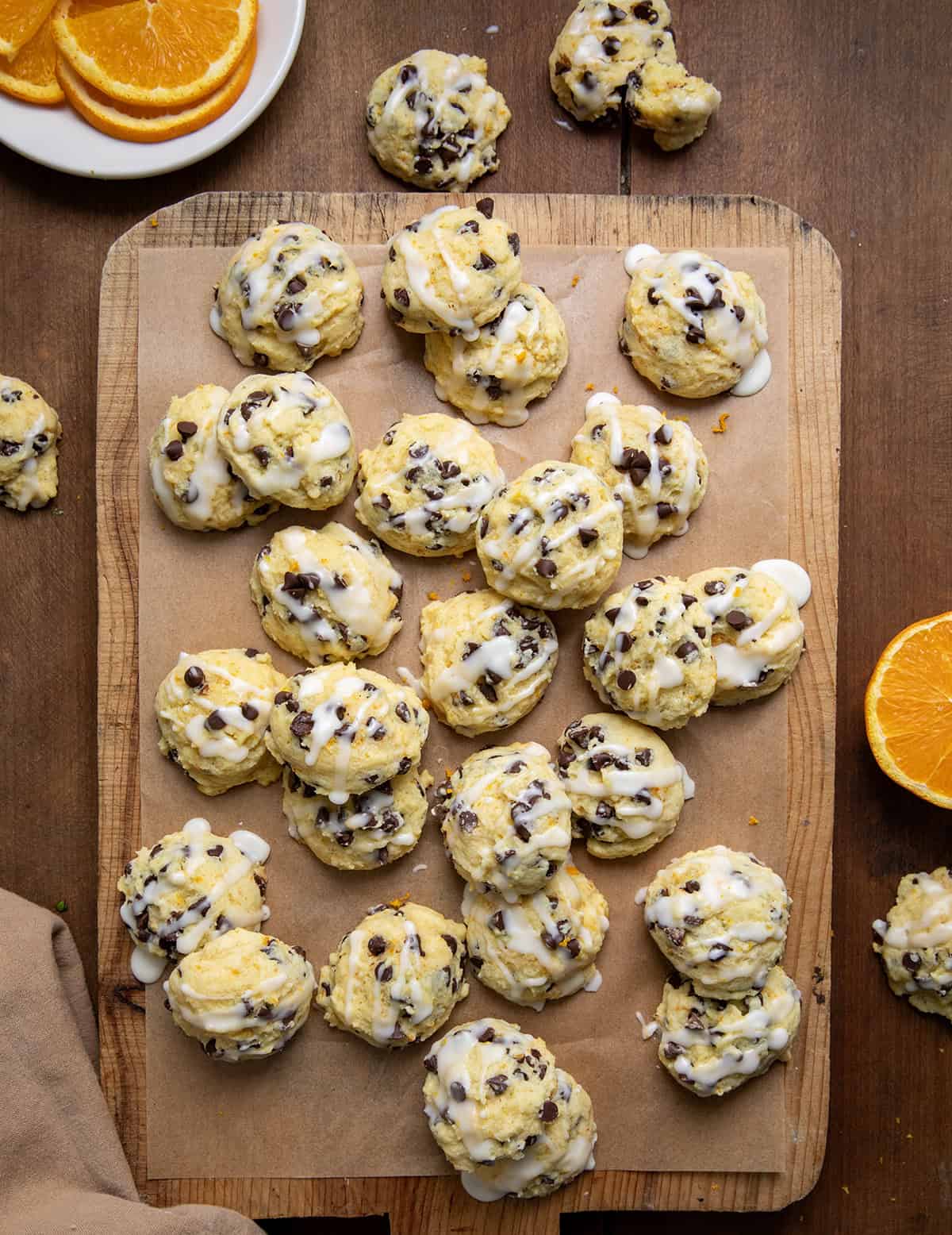 Orange Chocolate Chip Ricotta Cookies on a wooden table with oranges from overhead.