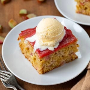 Piece of Rhubarb Cake With Rhubarb Sauce on it topped with vanilla ice cream.