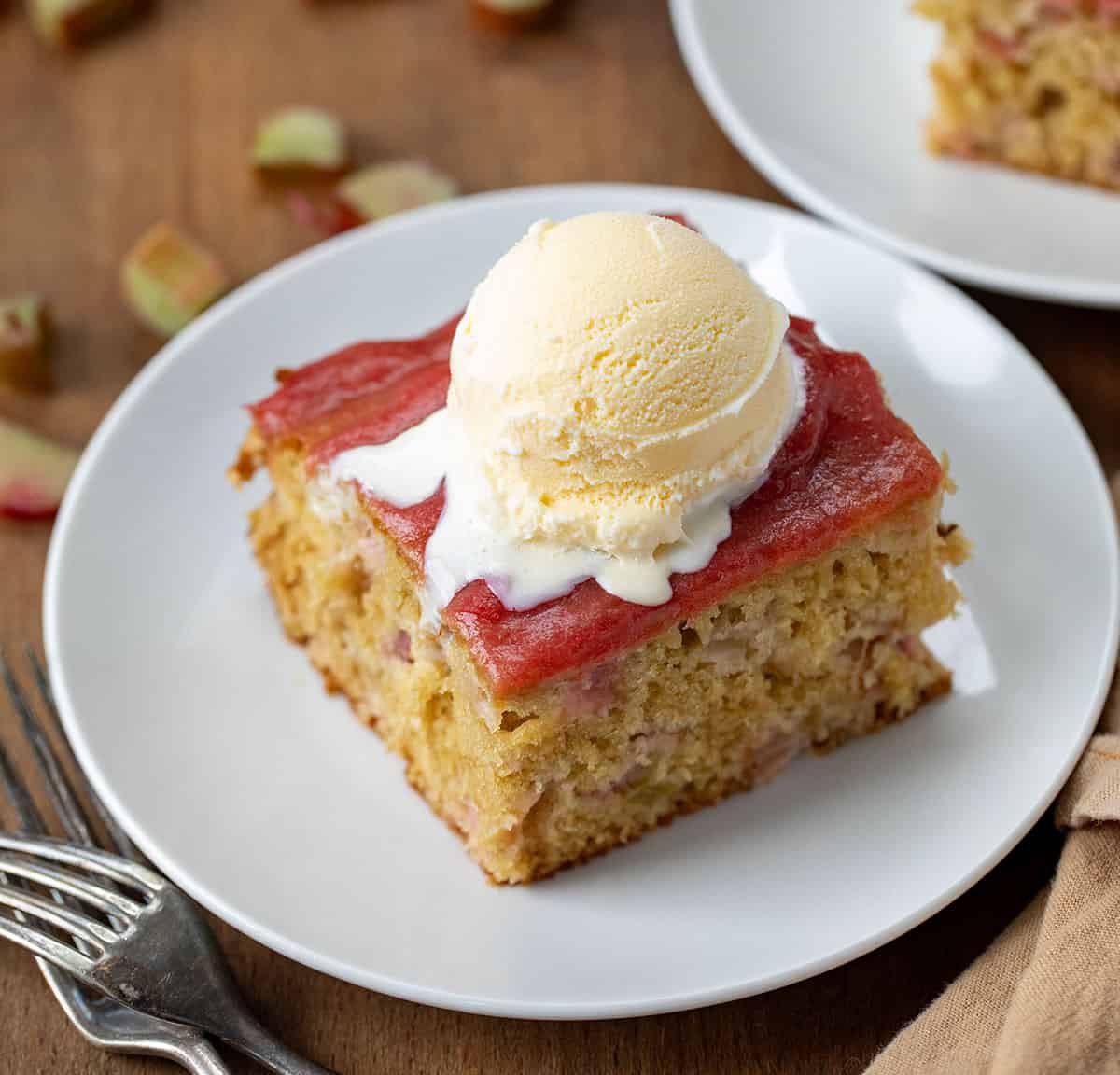 Piece of Rhubarb Cake With Rhubarb Sauce on it topped with vanilla ice cream. 