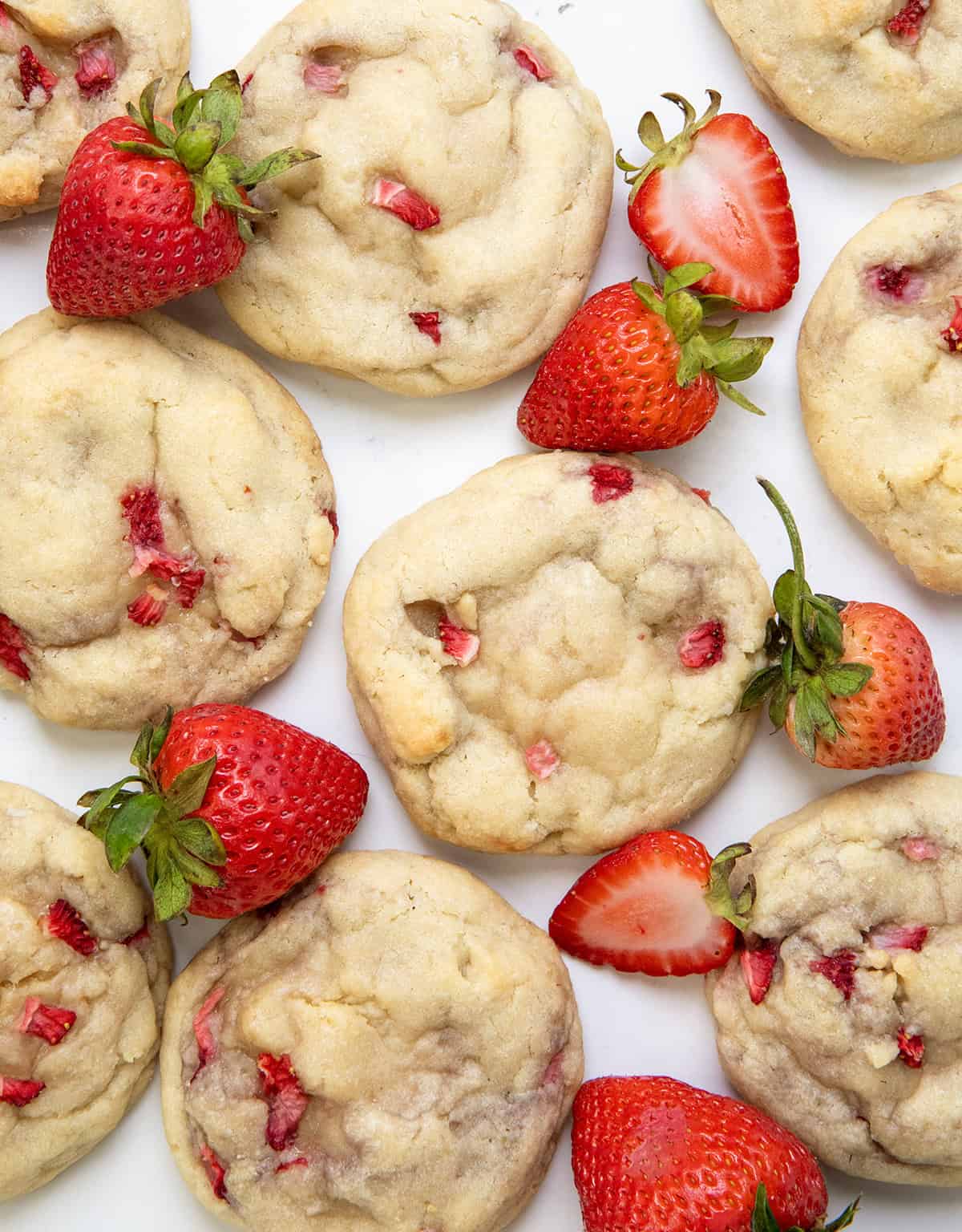 Strawberry Banana Cheesecake Cookies on a white table surrounded by strawberries and a banana.