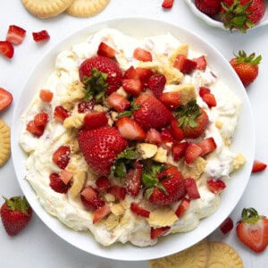 Strawberry Shortcake Cookie Salads in bowls on a white counter surrounded by shortbread cookies and strawberries.