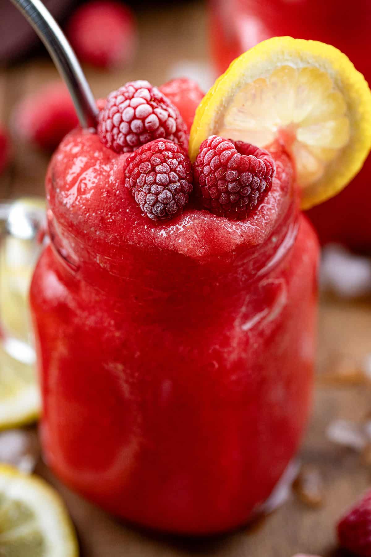 Close up of one Frozen Raspberry Lemonade with raspberry and lemon garnish.
