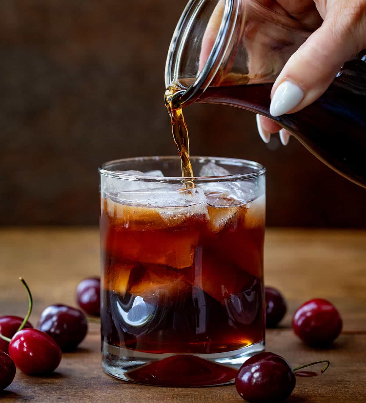 Pouring Cherry Bounce into a glass of ice.