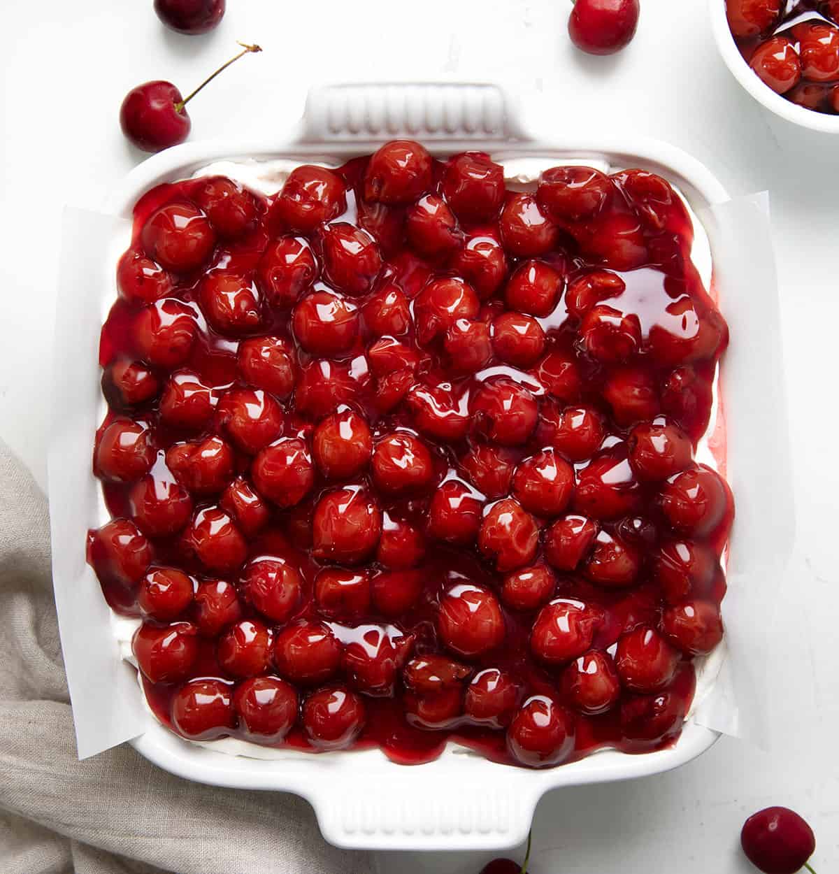 Pan of Cherry Delight on a white table from overhead with fresh cherries around. 