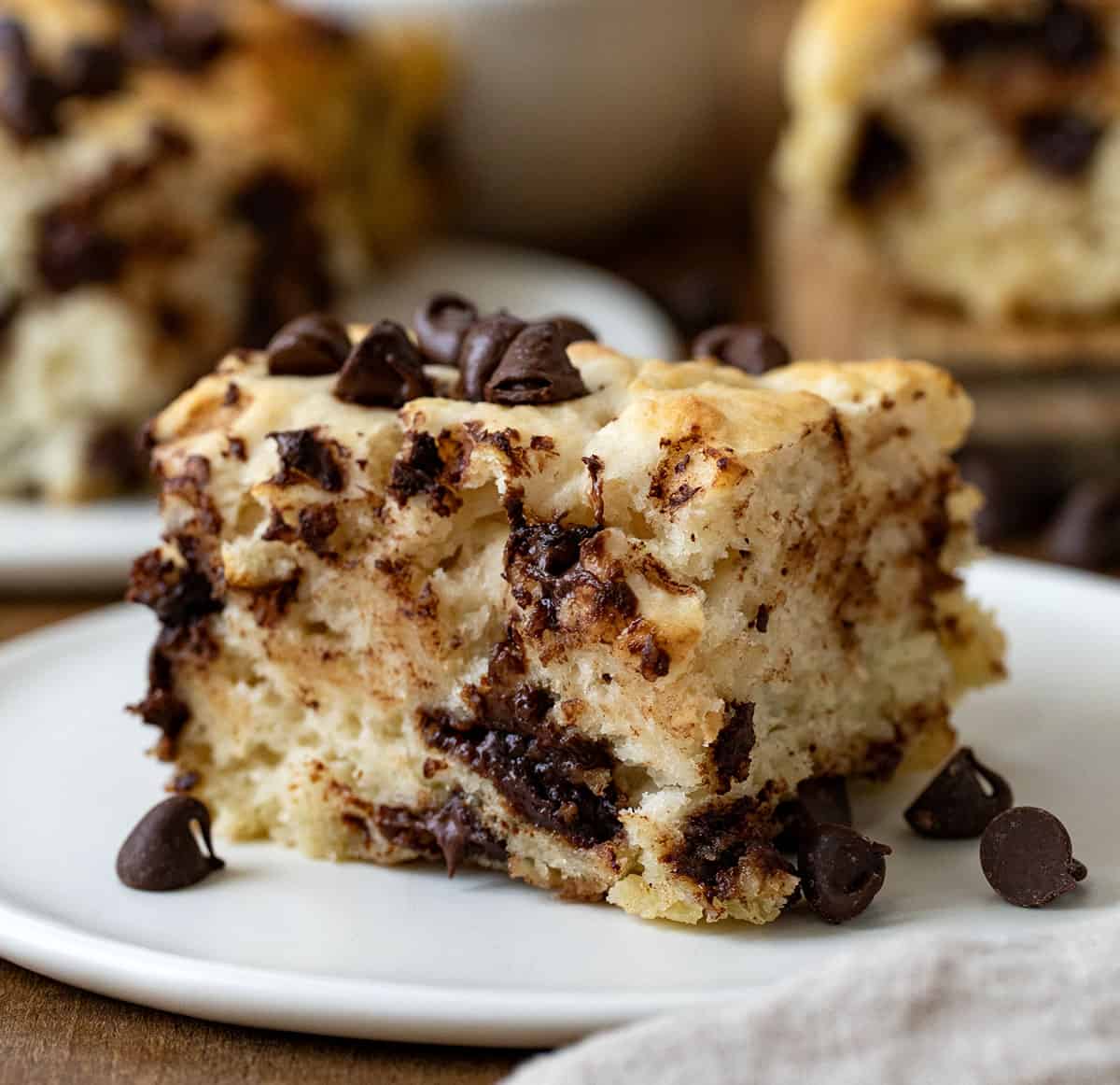 One Chocolate Chip Butter Swim Biscuit on a plate on a wooden table.