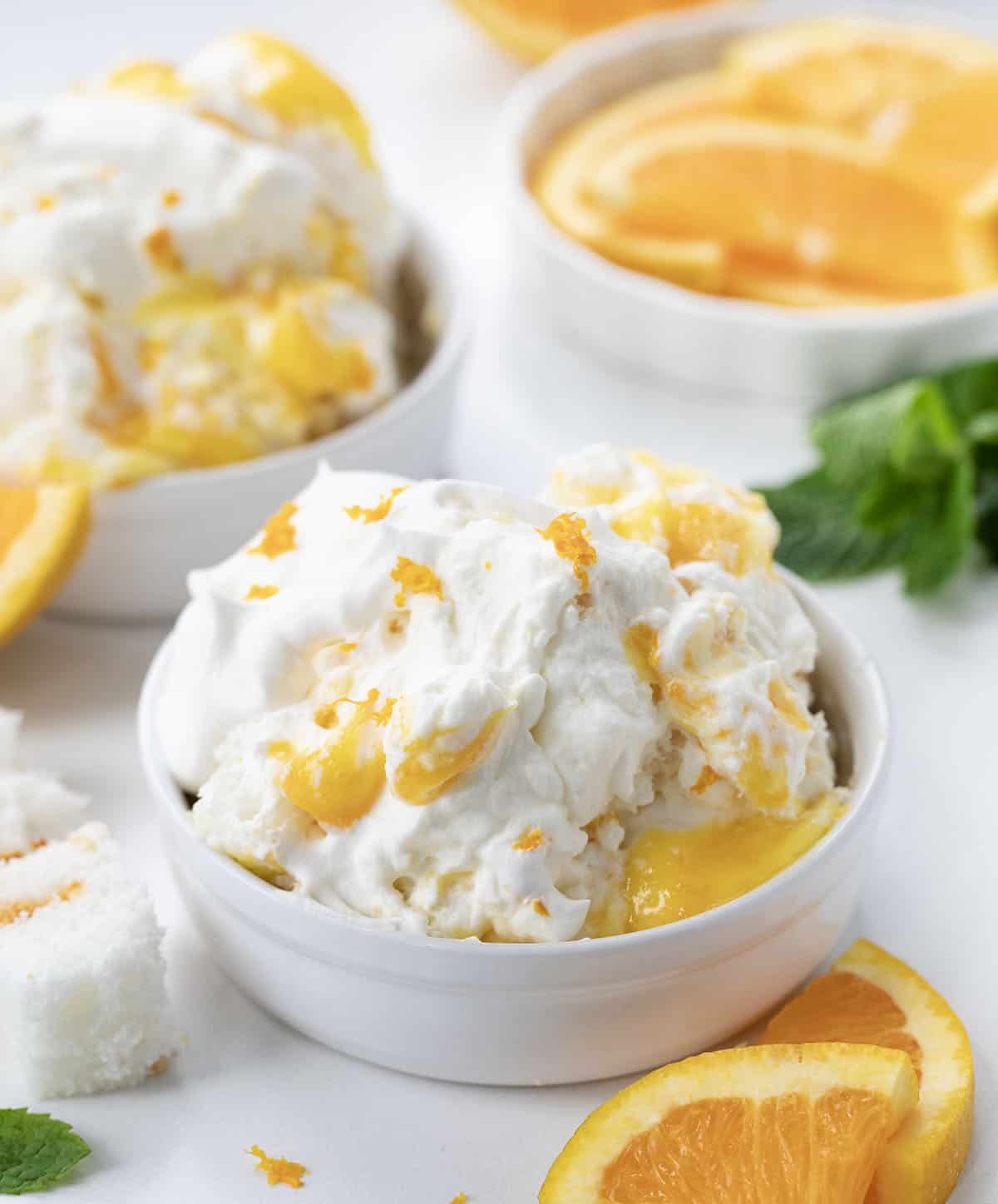 Individual portions of Creamsicle Trifle on a white counter surrounded by oranges and mint.