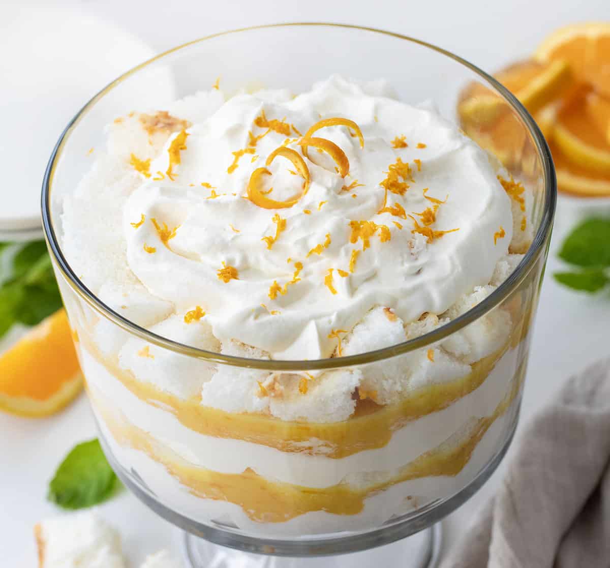 Top of an Creamsicle Trifle on a white counter surrounded by oranges and mint.