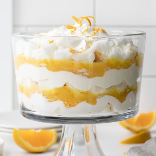 Straight on view of Creamsicle Trifle on a white counter surrounded by oranges and mint.