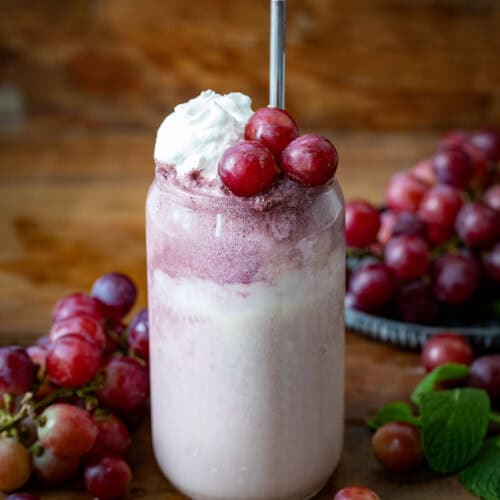 Dirty Grape Float on a wooden table surrounded by fresh grapes.