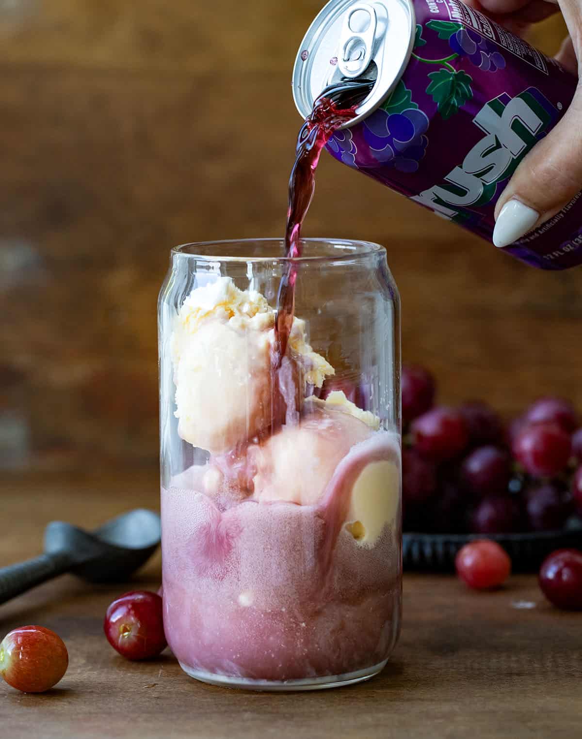 Pouring grape soda over ice cream and vodka to make a Dirty Grape Float.