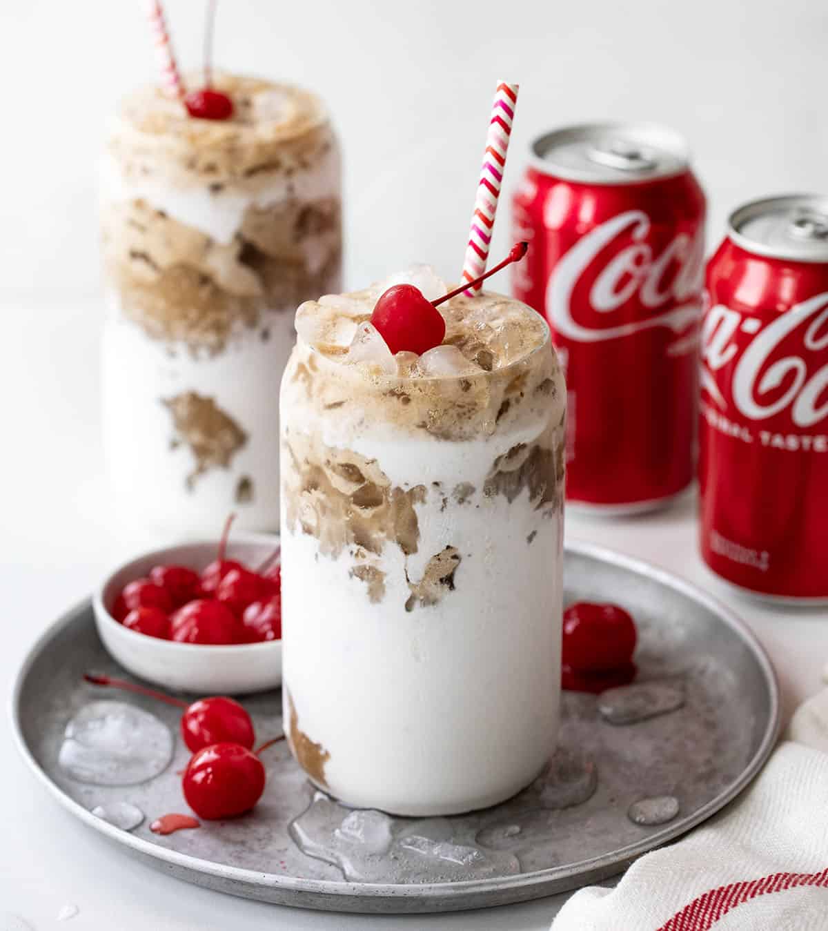 Fluffy Cokes on a white table top with cans of Coca Cola.