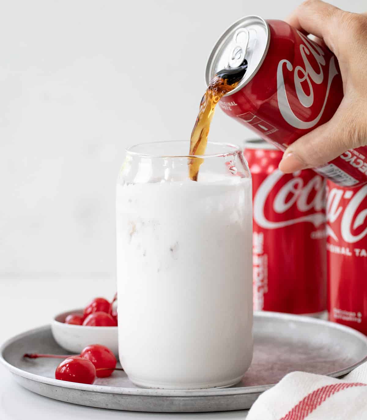 Pouring Coke into a glass that is coated with marshmallow fluff.