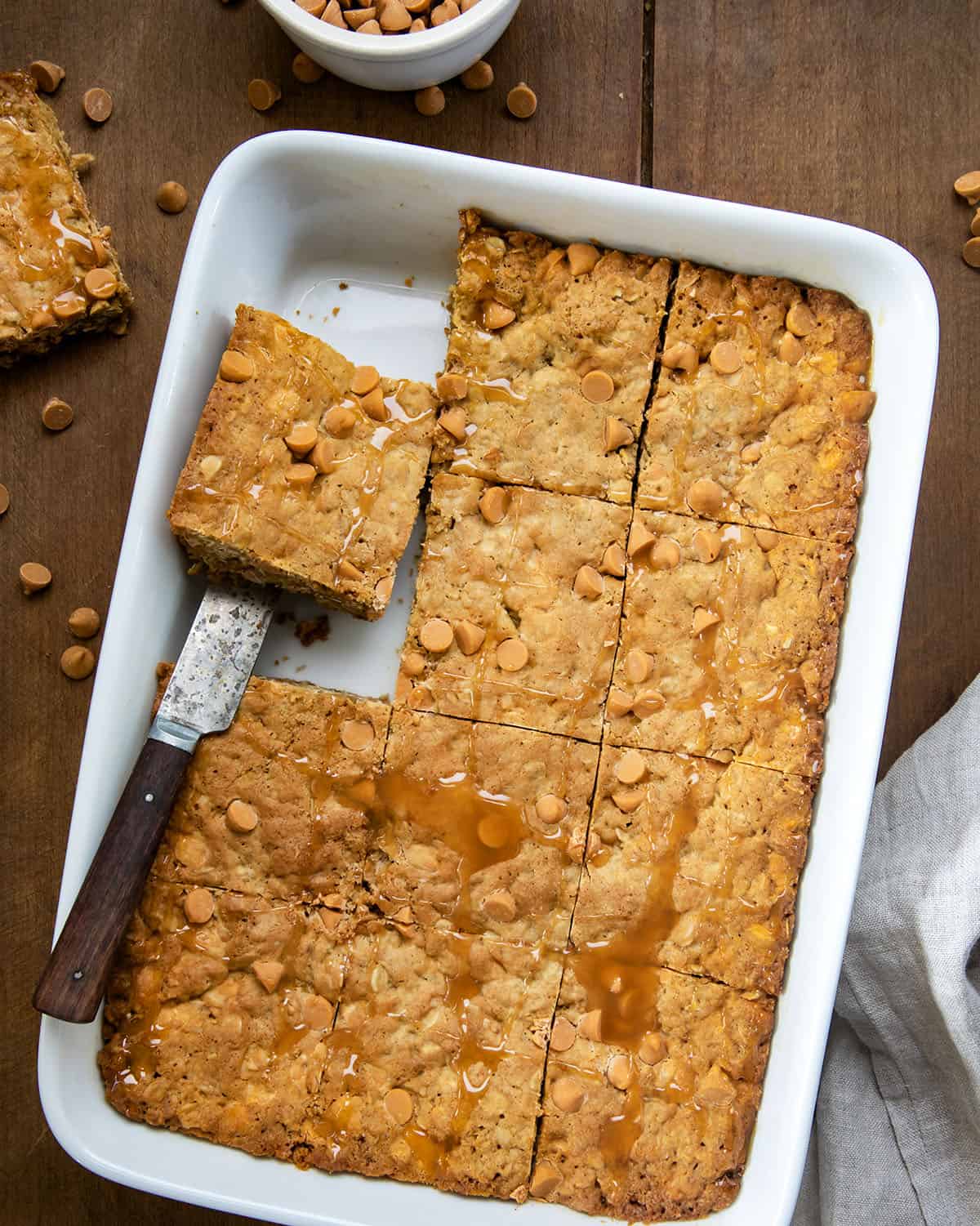 Oatmeal Butterscotch Bars in a pan with one bar removed and another about to be removed.