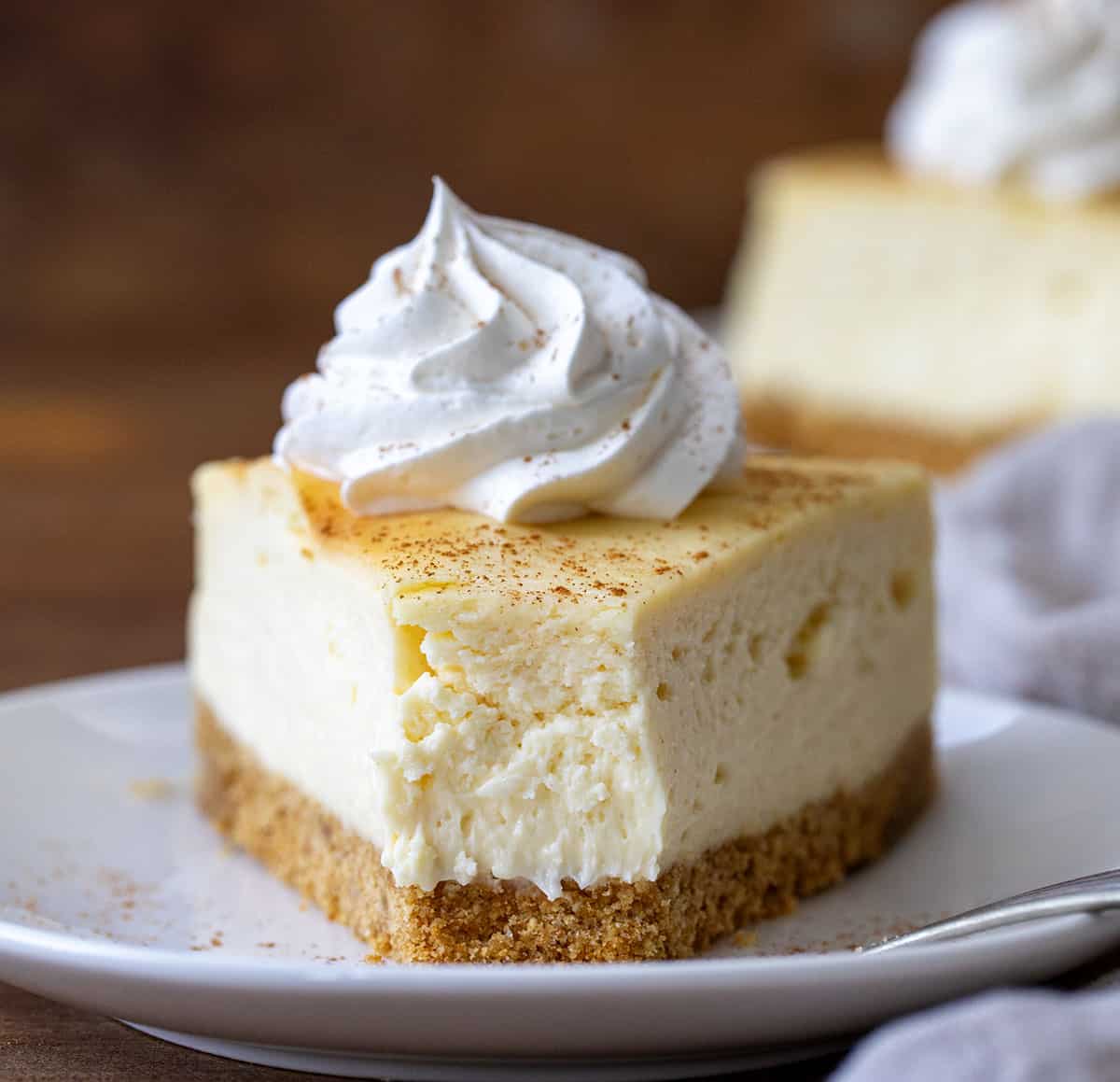 Piece of RumChata Cheesecake on a white plate with one bite removed.