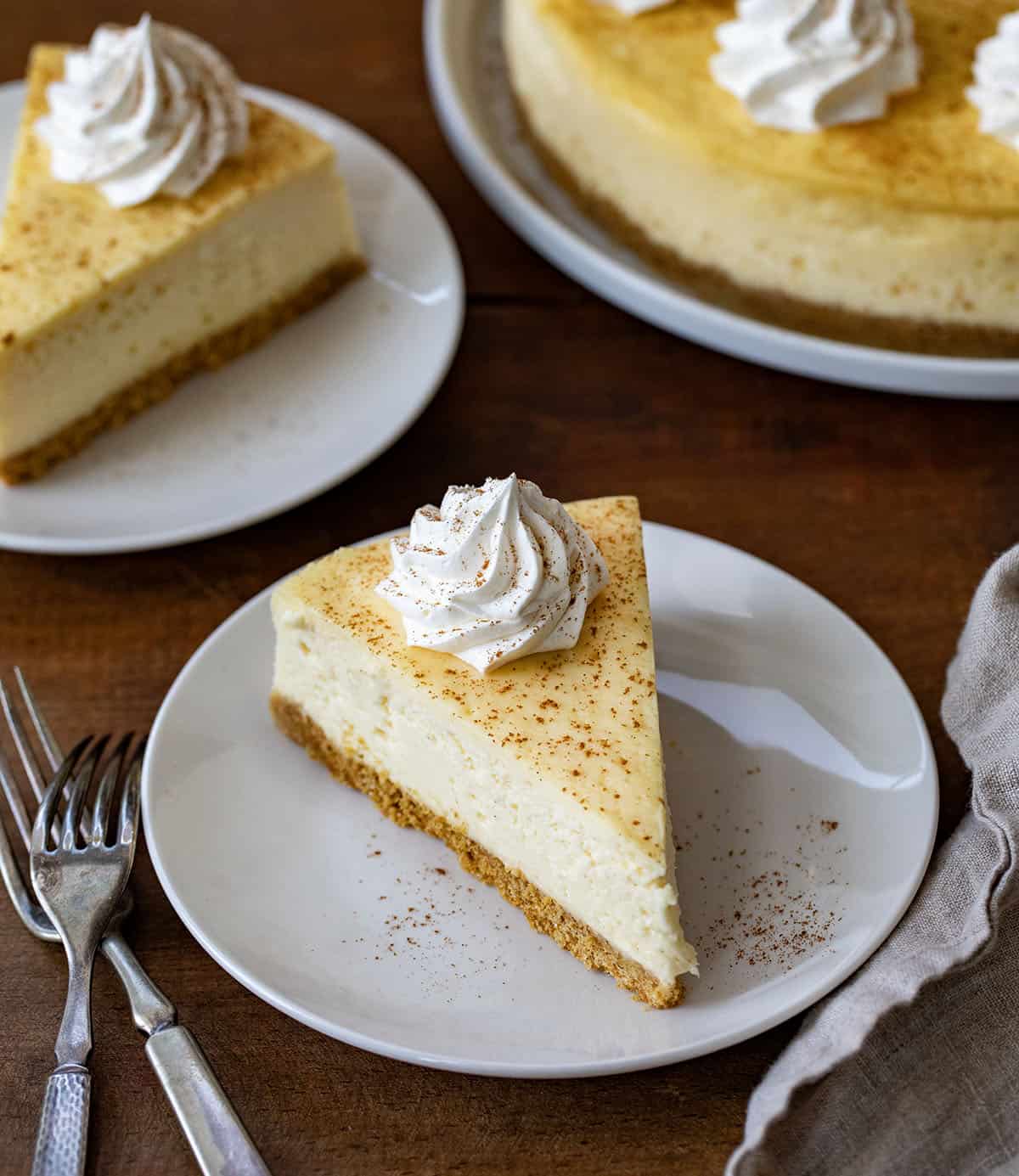 Slices of RumChata Cheesecake on plates on a wooden table.