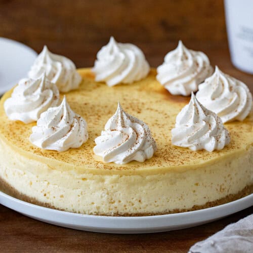 RumChata Cheesecake on a white cake plate on a wooden table.