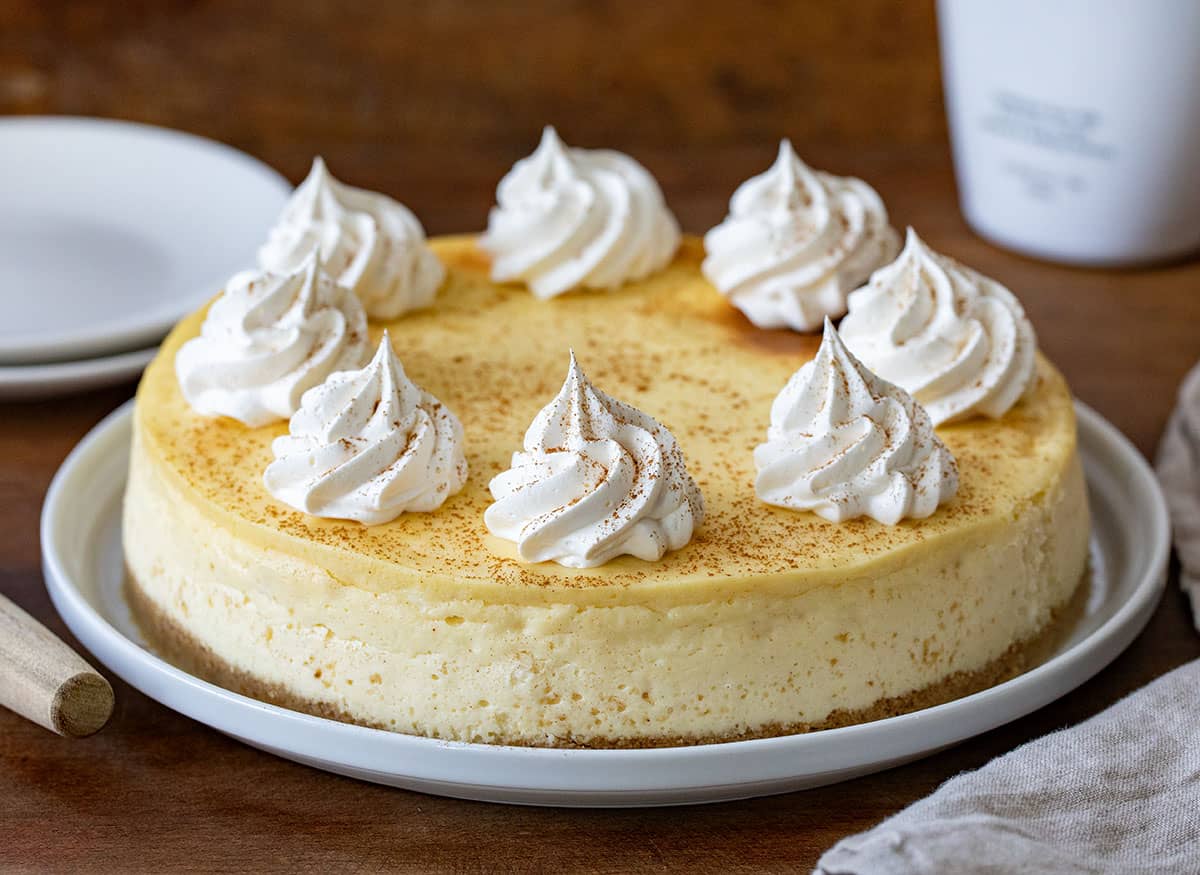 RumChata Cheesecake on a white cake plate on a wooden table. 