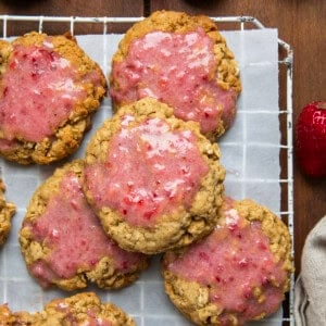 Strawberry Iced Oatmeal Cookies on a rack on a wooden table from overhead.