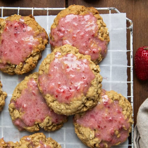 Strawberry Iced Oatmeal Cookies on a rack on a wooden table from overhead.