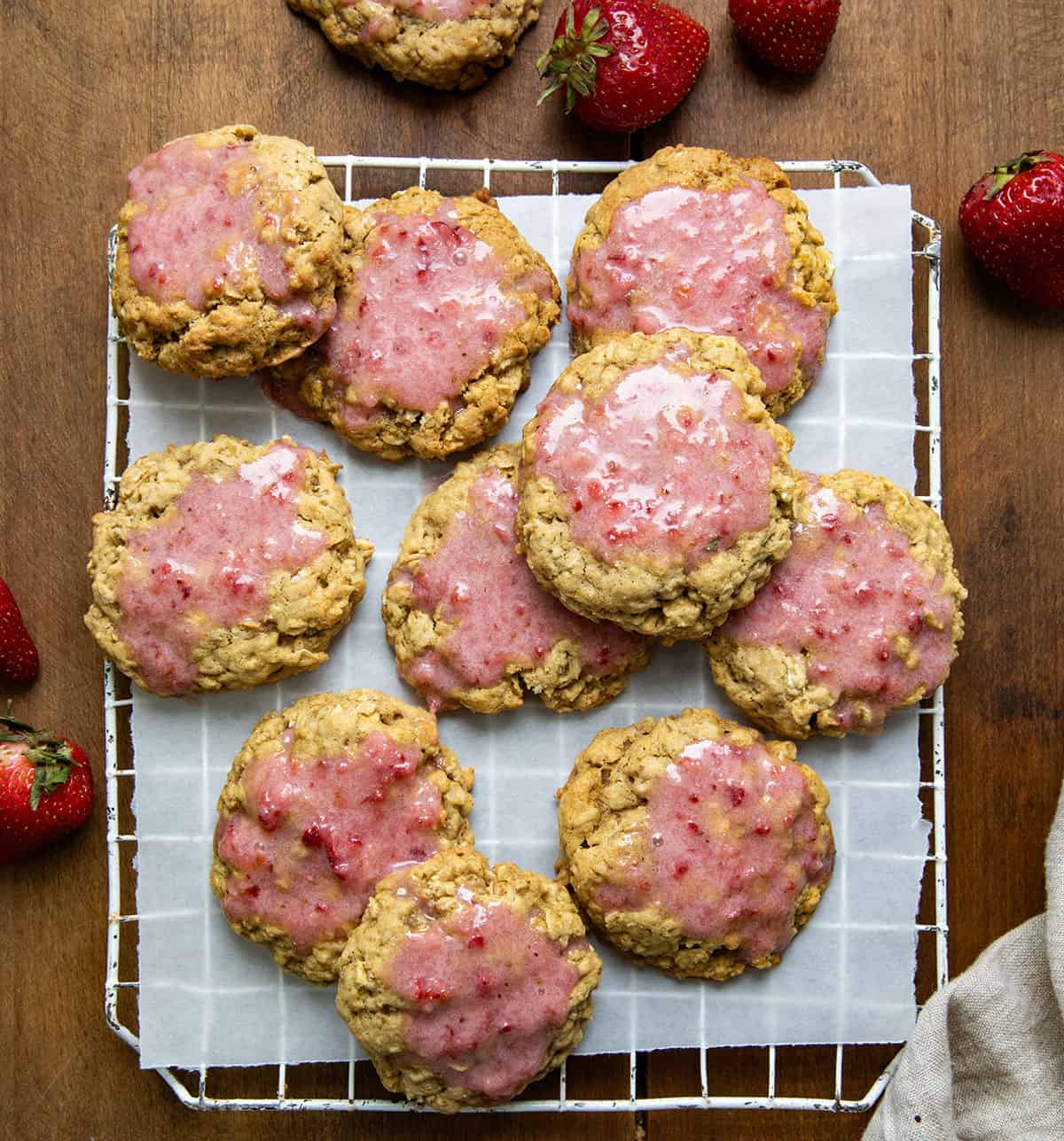 Strawberry Iced Oatmeal Cookies on a rack on a wooden table from overhead.