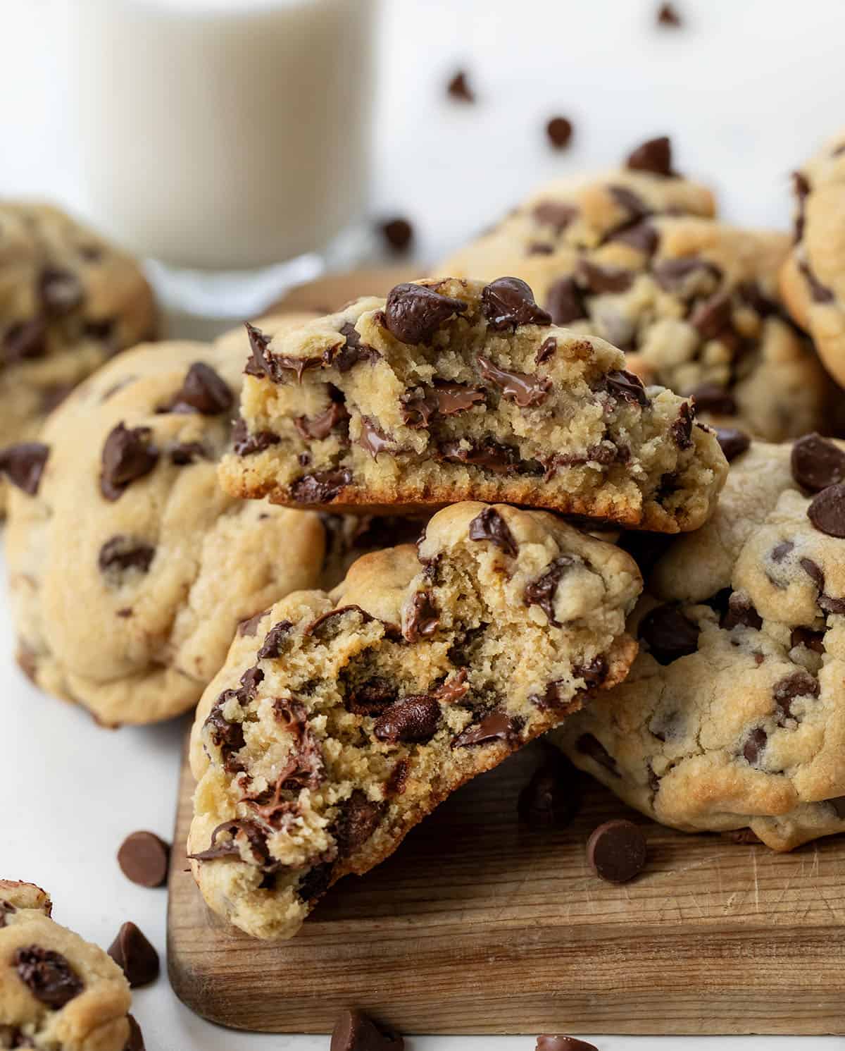 A pile of Chocolate Chip Cookies with one broken showing gooey texture inside.