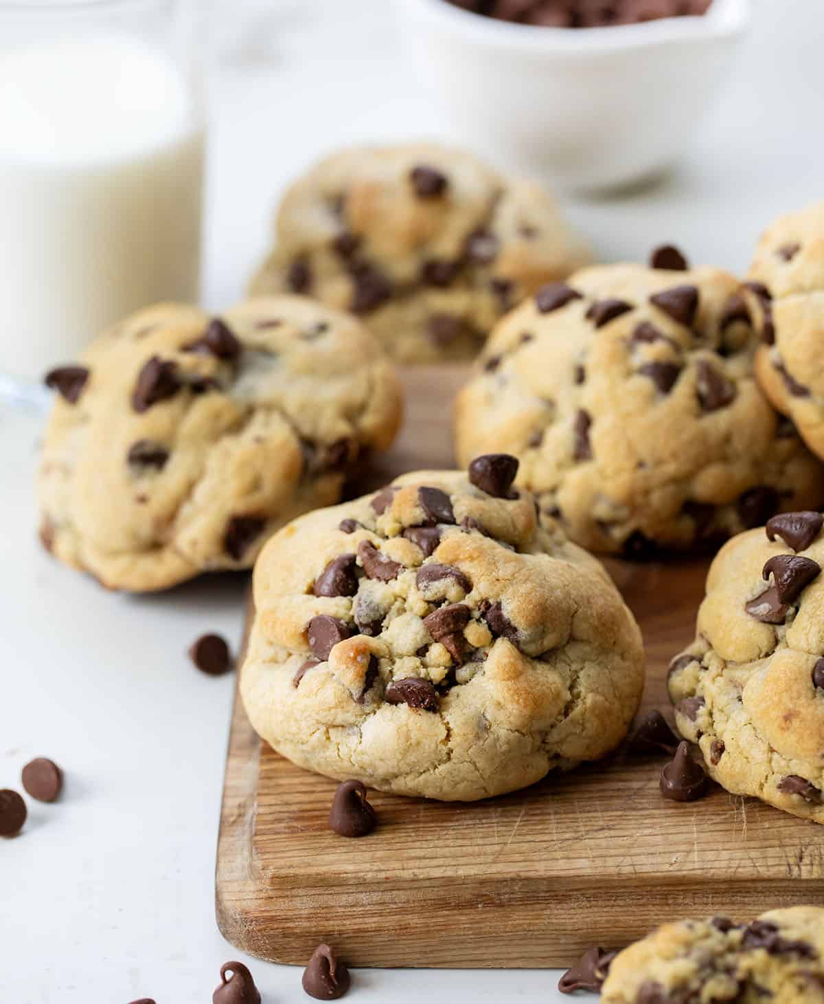 Ultimate Thick and Chewy Chocolate Chip Cookies on a cutting board with milk.