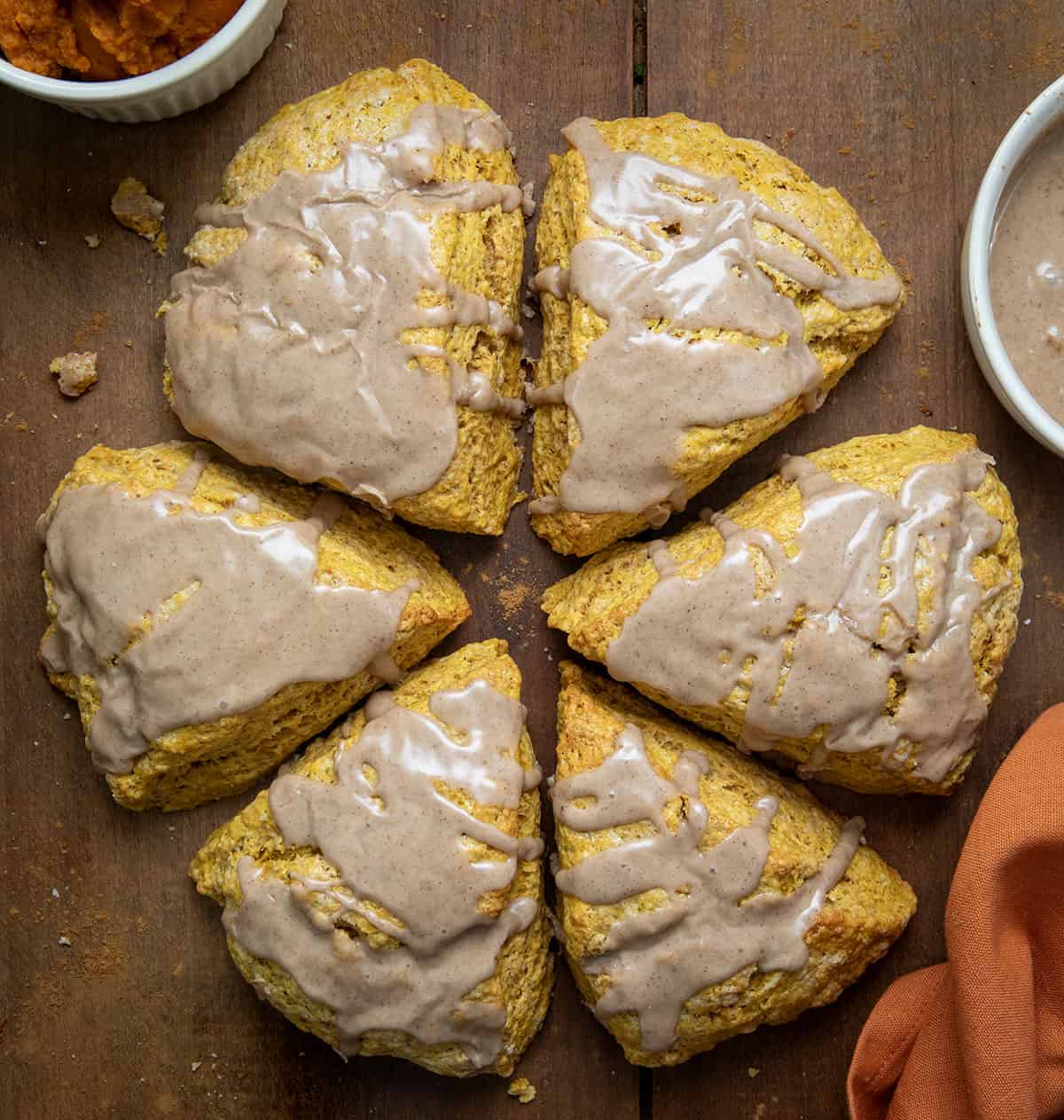 Pumpkin Scones with glaze on a wooden table from overhead. 