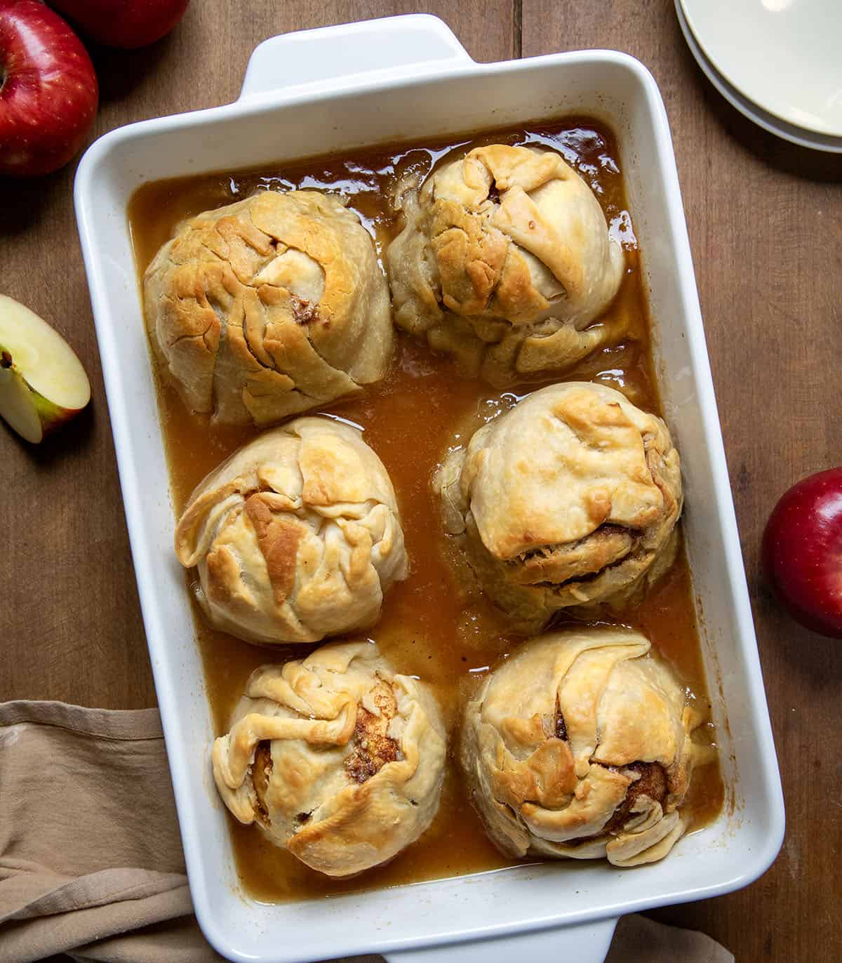 Pan of Apple Dumplings on a wooden table with fresh apples from overhead.