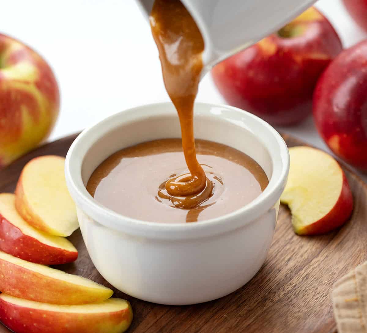 Drizzling Apple Cider Caramel Sauce into a white cup.