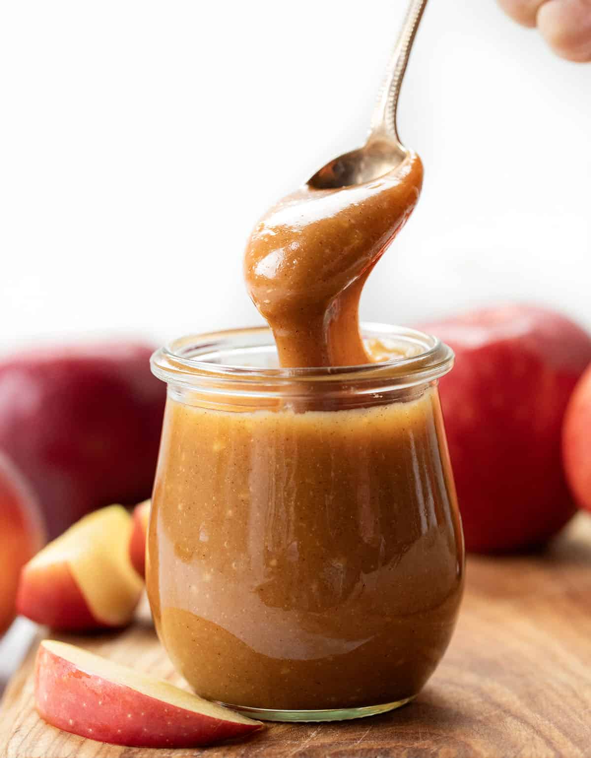 Spoon picking up Apple Cider Caramel Sauce from jar.