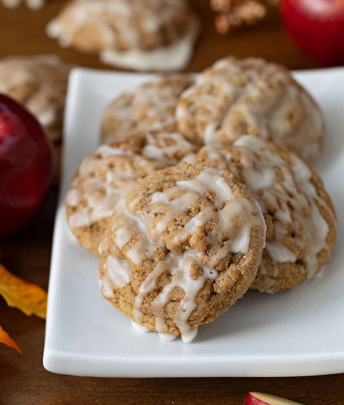 Plate of Apple Cider Cookies on a wooden table with fresh apples.