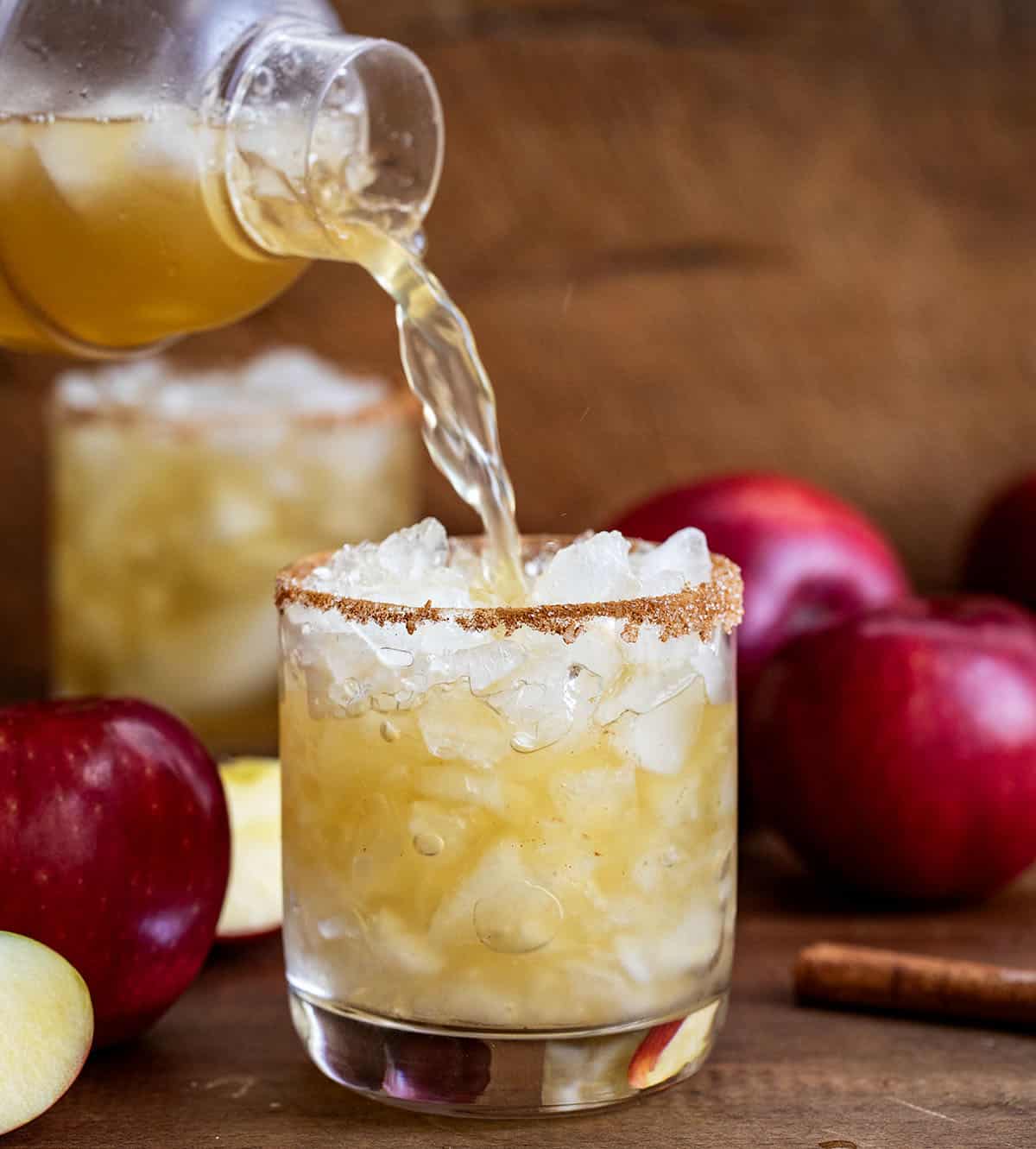 Pouring margarita mixture into a rimmed glass.