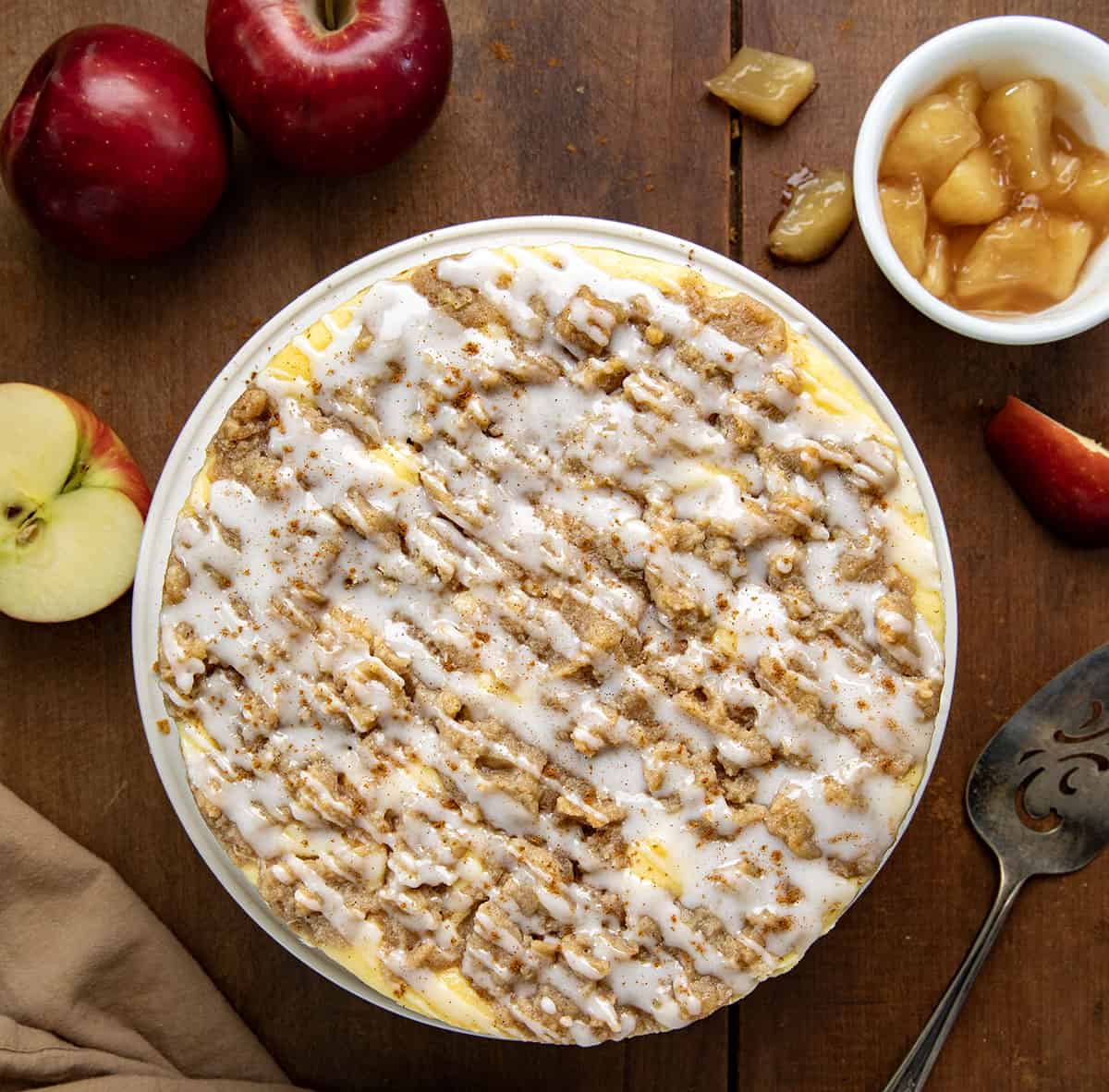 Apple Crumble Cheesecake on a wooden table with apples from overhead.