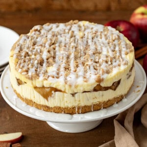 Apple Crumble Cheesecake on a cake stand on a wooden table.